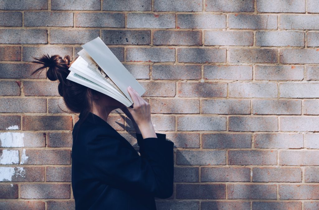 Girl with book over face